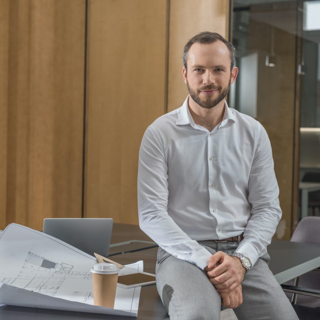 handsome architect sitting on table with plans at office - Digital Web Nova